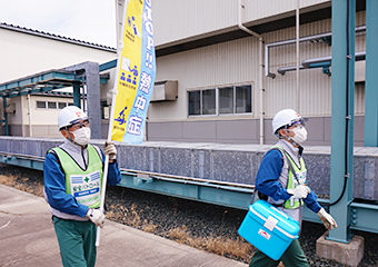 飲料水と熱中症注意喚起の旗を持って巡回する社員